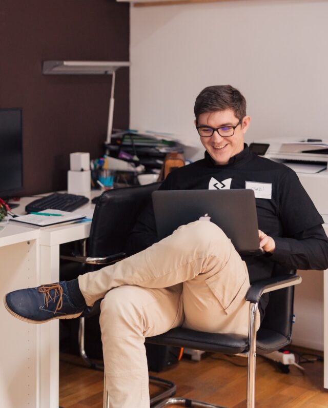 Man smiling and sitting with a laptop
